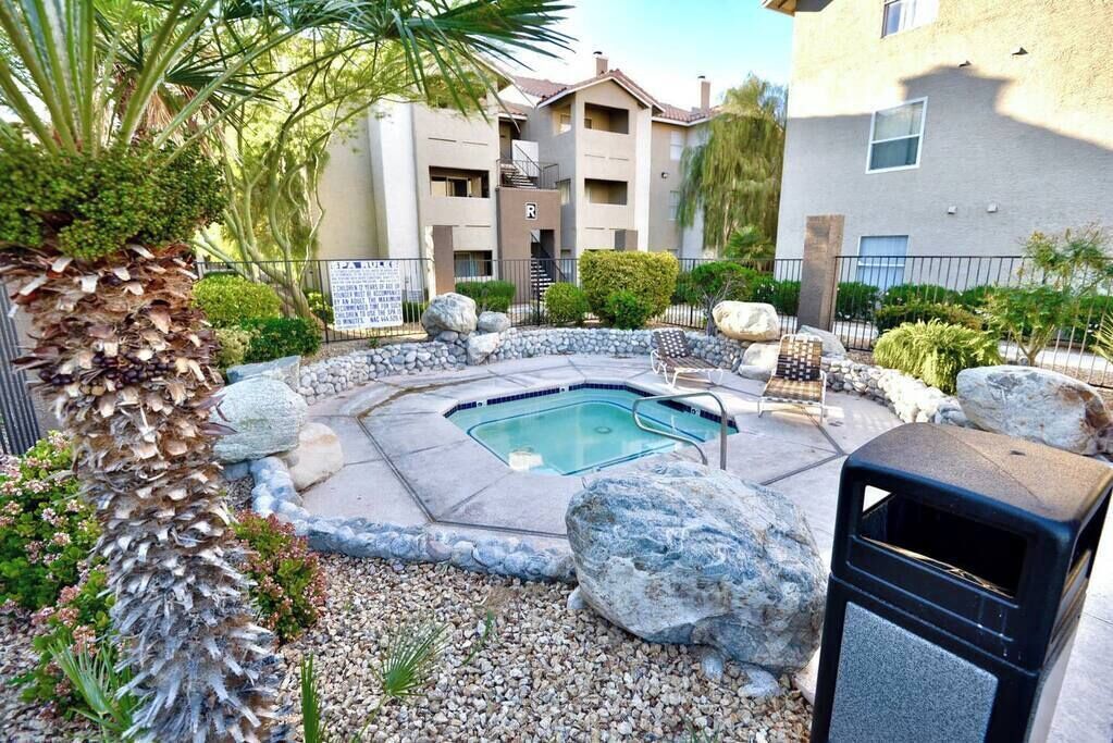 Un edificio residencial con piscina, rodeado de rocas y plantas.