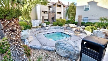 Un edificio residencial con piscina, rodeado de rocas y plantas.