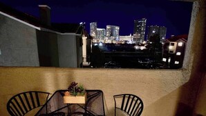 A balcony with a table and chairs, overlooking a city skyline at night. - Chelsea Suite 2b/2b Strip View! (Las Vegas)