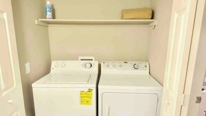 A laundry room with two white washing machines and a shelf above them. - Chelsea Suite 2b/2b Strip View! (Las Vegas)