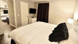 A hotel room with a bed, a television, a desk, and a bathroom visible in the background. - Chelsea Suite 2b/2b Strip View! (Las Vegas)