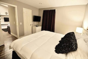 A hotel room with a bed, a television, a desk, and a bathroom visible in the background. - Chelsea Suite 2b/2b Strip View! (Las Vegas)