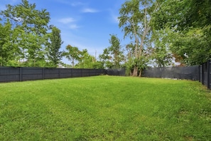 A grassy backyard with a black fence and trees. - Peaceful Dayton Cottage Near Downtown (Dayton)