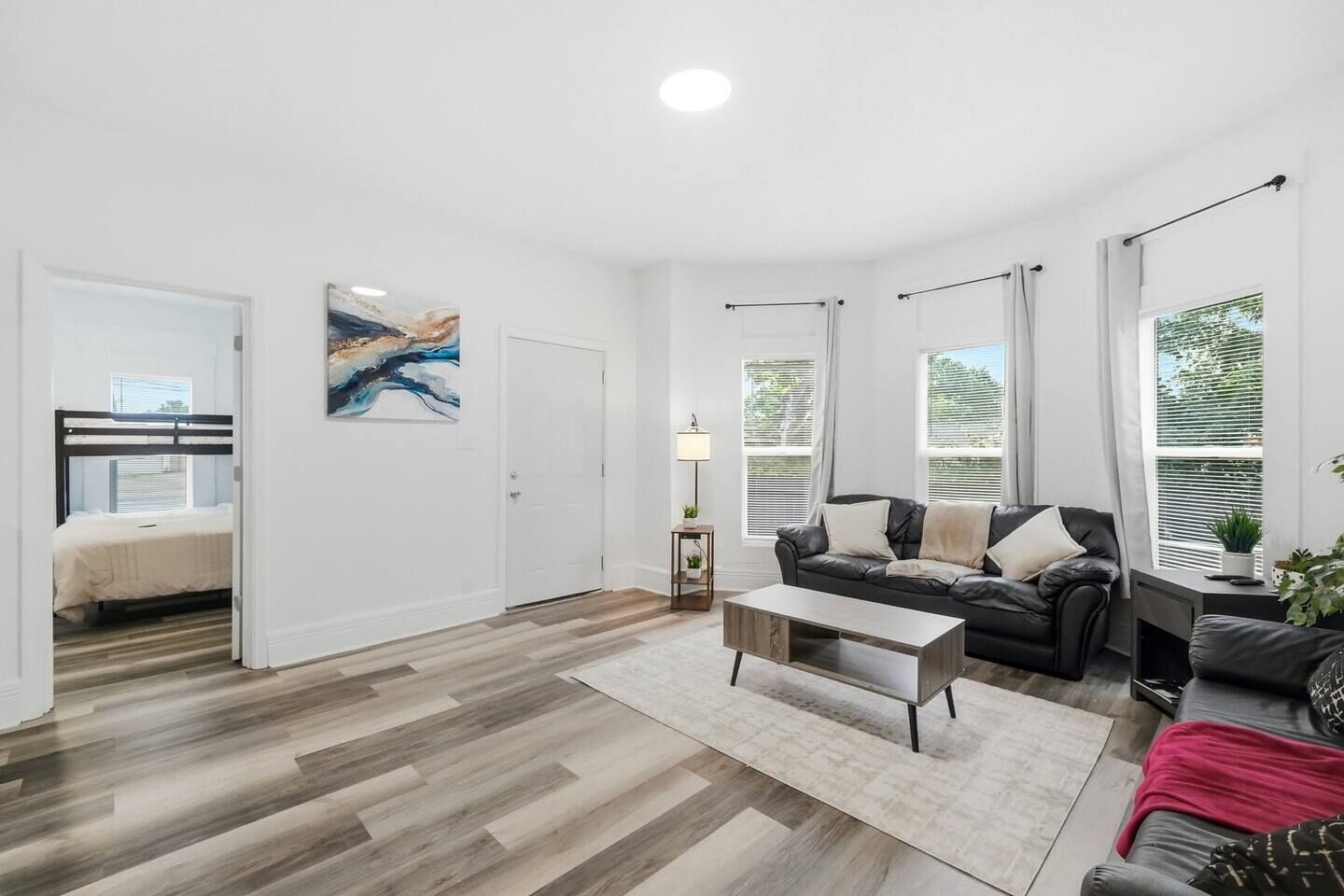 A modern living room with a sofa, coffee table, and a painting on the wall.