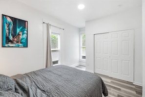 Un dormitorio con cama, puerta y ventana.