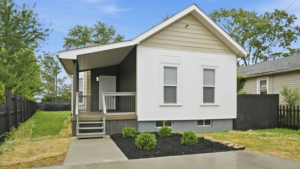 A single-story house with a front porch, a small entryway, and a front yard with a garden bed and a fence. - Peaceful Dayton Cottage Near Downtown (Dayton)