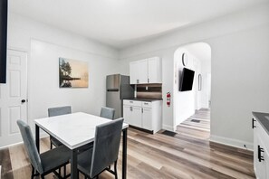 A modern kitchen with white cabinets, a stainless steel refrigerator, and a flat-screen TV mounted on the wall. - Peaceful Dayton Cottage Near Downtown (Dayton)