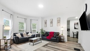A modern living room with two sofas, a coffee table, and a TV. - Peaceful Dayton Cottage Near Downtown (Dayton)