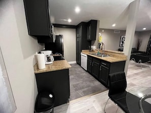 A modern kitchen with black cabinets, a granite countertop, and a dishwasher. - Eden Suite 2b/2b fully furnished (Las Vegas)