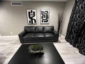 A modern living room with a black leather sofa, a black coffee table with a plant, and abstract art on the wall. - Eden Suite 2b/2b fully furnished (Las Vegas)