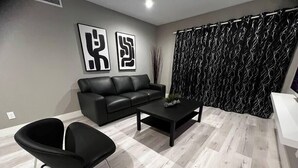 Un salon moderne avec un canapé en cuir noir, une table basse noire et un fauteuil noir.