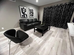 Ein modernes Wohnzimmer mit einem schwarzen Ledersofa, einem schwarzen Couchtisch und einem schwarzen Sessel.