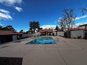 A swimming pool with a clear blue sky, surrounded by buildings with red-tiled roofs. - Sundance Suite 2B/2B Central (Las Vegas)