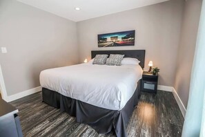 A hotel room with a large bed, a nightstand with a lamp, and a painting on the wall. - Sundance Suite 2B/2B Central (Las Vegas)
