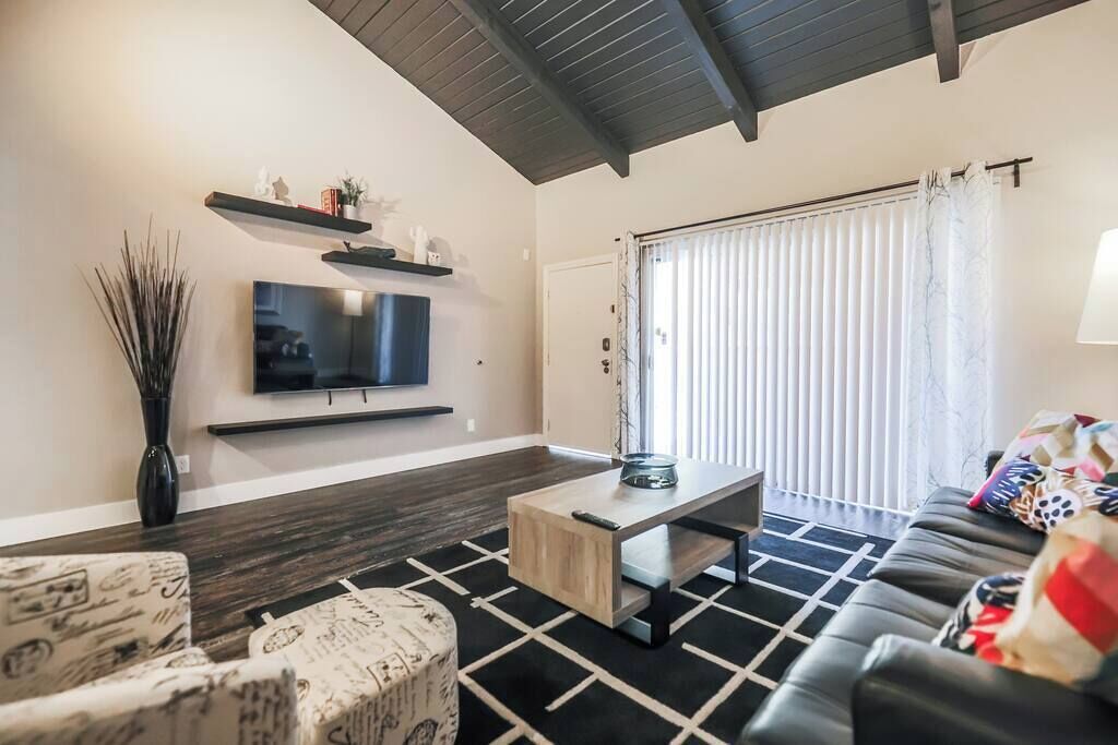 Een moderne woonkamer met een flatscreen televisie, een salontafel en een bank.