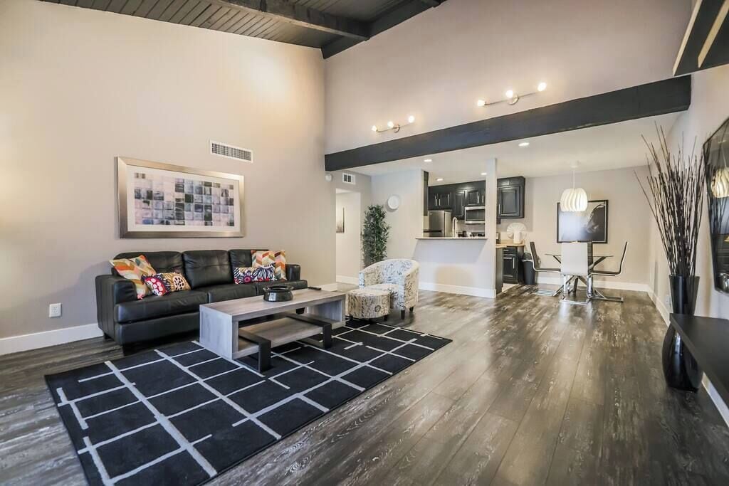 A modern living room with a black sofa, a coffee table, and a patterned rug.