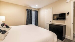 Ein Hotelzimmer mit Bett, Schreibtisch, Fernseher und Tür.