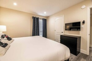A hotel room with a bed, a desk, a television, and a door. - Dalia Suite 2b/1b Near UNLV (Las Vegas)