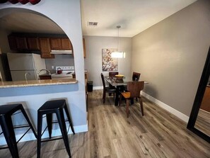 Une cuisine moderne avec un coin repas, un plancher en bois et un luminaire suspendu.