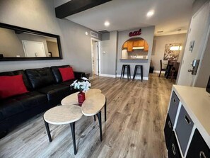 Ein modernes Wohnzimmer mit einer schwarzen Ledersofa, einem Couchtisch und einer Küchenzeile mit Bar.