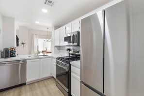 Une cuisine moderne avec des meubles blancs, des appareils en acier inoxydable et un îlot central.