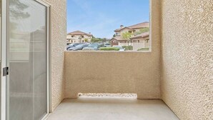 En balkong med utsikt över ett bostadsområde, en dörr och en vägg med en tydlig yta.