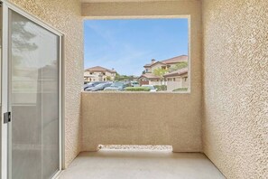 A balcony with a view of a residential area, a door, and a textured wall. - Belmont Suite Modern 2 /2 condo (Las Vegas)