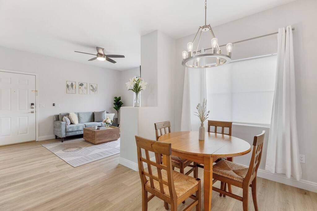 Un coin repas avec une table ronde en bois et des chaises, un ventilateur de plafond et un lustre.
