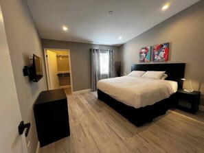 A bedroom with a bed, bedside tables, a wardrobe, and a door leading to a bathroom. - Huntley Suite Luxury 2b/2b condo (Las Vegas)