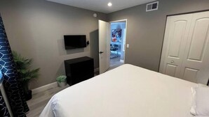 A bedroom with a bed, a television mounted on the wall, a door, and a small plant. - Huntley Suite Luxury 2b/2b condo (Las Vegas)