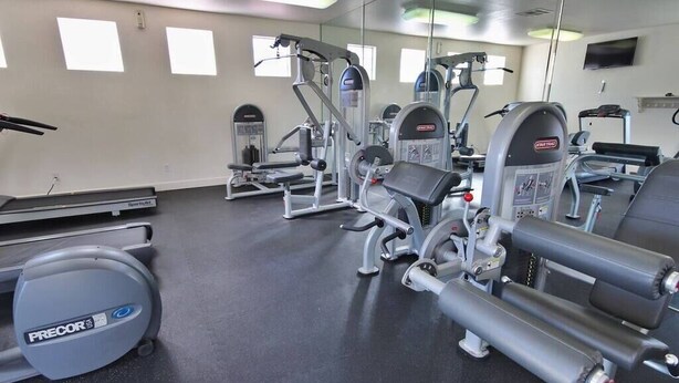 A gym with various exercise machines, a treadmill, and a mirrored wall. - Huntley Suite Luxury 2b/2b condo (Las Vegas)