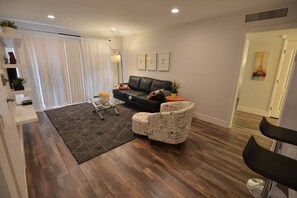 A modern living room with a black leather sofa, patterned armchair, and a geometric rug. - Park Suite 1B/1B Close to strip (Las Vegas)