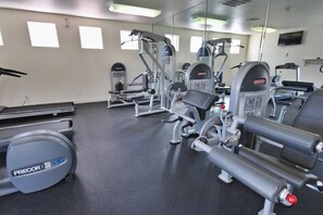 Ein Fitnessraum mit verschiedenen Trainingsgeräten, Laufbändern und einer Spiegelwand.