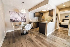 Een moderne keuken met een eethoek, met een ronde tafel en stoelen, een grote hanglamp en een stadsgezicht op de muur.