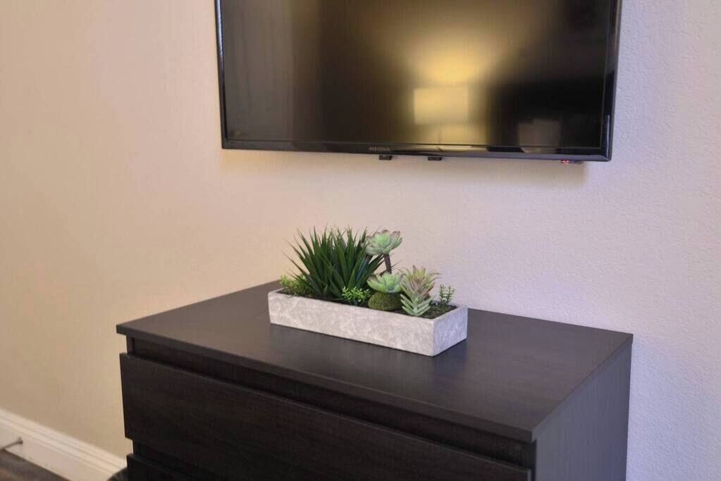 Et mørkt kommode med en rektangulær plantekasse med grønne planter ovenpå.