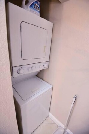 A laundry area with a washing machine and dryer, a mop, and a detergent bottle on top of the dryer. - Ava Suite 1 B/1B close to strip (Las Vegas)