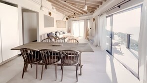 A spacious dining area with a long table and chairs, a ceiling fan, and large windows offering a view of the outside. - Suite 35: 2-Bedroom Ocean-View Suite with Wraparound Terrace, Antigua (Urlings)