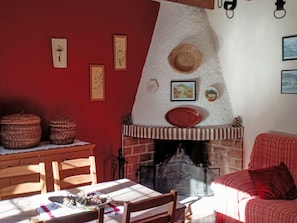 A cozy living room with a fireplace, a dining table with chairs, and a red sofa. - La Atalaya de Los Romanes: Tourismus und Urlaub. by Interhome (Los Romanes)