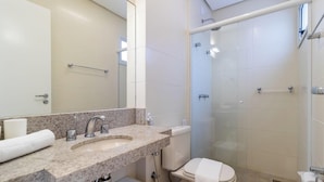 Un bagno con lavabo in marmo, un water, una doccia con porta in vetro e un porta asciugamani.