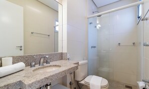 Une salle de bain moderne avec un lavabo surmonté d’un plan de travail en granit, une douche à parois de verre et des toilettes.