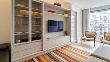 A modern living room with a large cabinet, a flat-screen TV, and a striped rug.