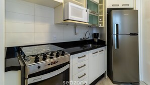 Una cucina moderna con piano cottura in acciaio inossidabile, forno a microonde integrato e frigorifero.
