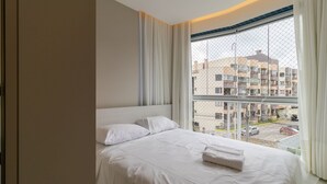 Camera d'albergo con un letto grande, vista sulla città attraverso una finestra e una tenda.