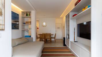 Una sala de estar moderna con un sofá, una mesa de comedor, sillas, un televisor y una estantería.