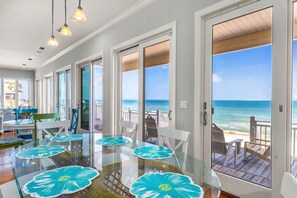 A spacious room with a glass table and chairs, large windows with ocean views, and a balcony with outdoor seating. - Sea Glass, Beach Front, Renovated, Community Pools, Beach Gear Credit! (St. George Island)