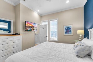 A bedroom with a bed, dresser, TV, and artwork. - Sea Glass, Beach Front, Renovated, Community Pools, Beach Gear Credit! (St. George Island)