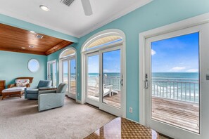 A room with a view of the ocean, featuring a large sliding glass door, a ceiling fan, and a seating area with a sofa and chairs. - Sea Glass, Beach Front, Renovated, Community Pools, Beach Gear Credit! (St. George Island)