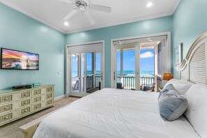A bedroom with a bed, a television, a dresser, and a balcony with a view of the ocean. - Sea Glass, Beach Front, Renovated, Community Pools, Beach Gear Credit! (St. George Island)