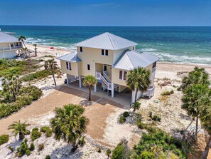 A two-story beachfront house with a balcony, surrounded by palm trees and a sandy beach. - Sea Glass, Beach Front, Renovated, Community Pools, Beach Gear Credit! (St. George Island)