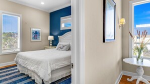 Een slaapkamer met een bed, een nachtkastje, een lamp, een inlijsting en een raam met uitzicht.